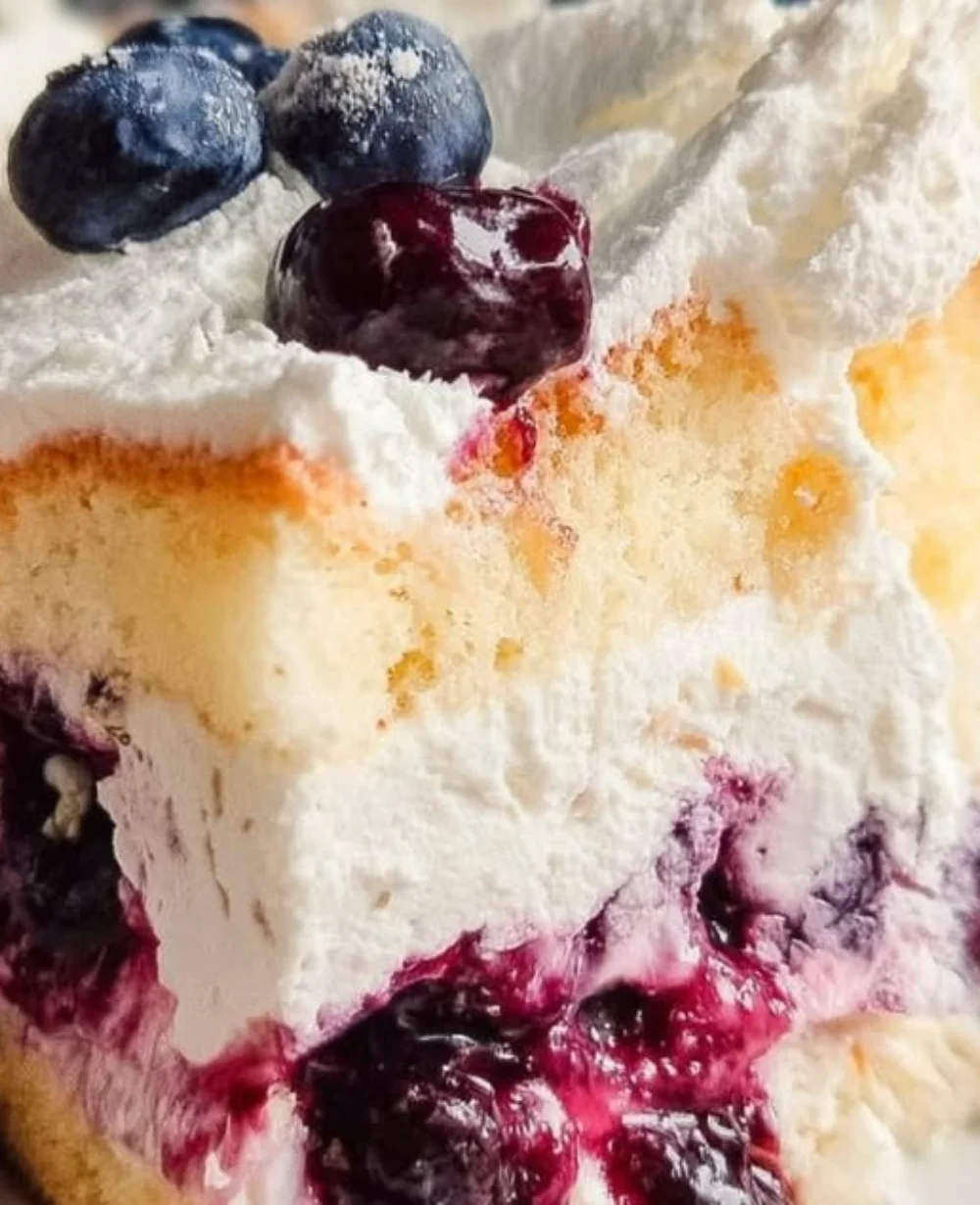 Delicious slice of Blueberry Cake topped with fresh blueberries and cream