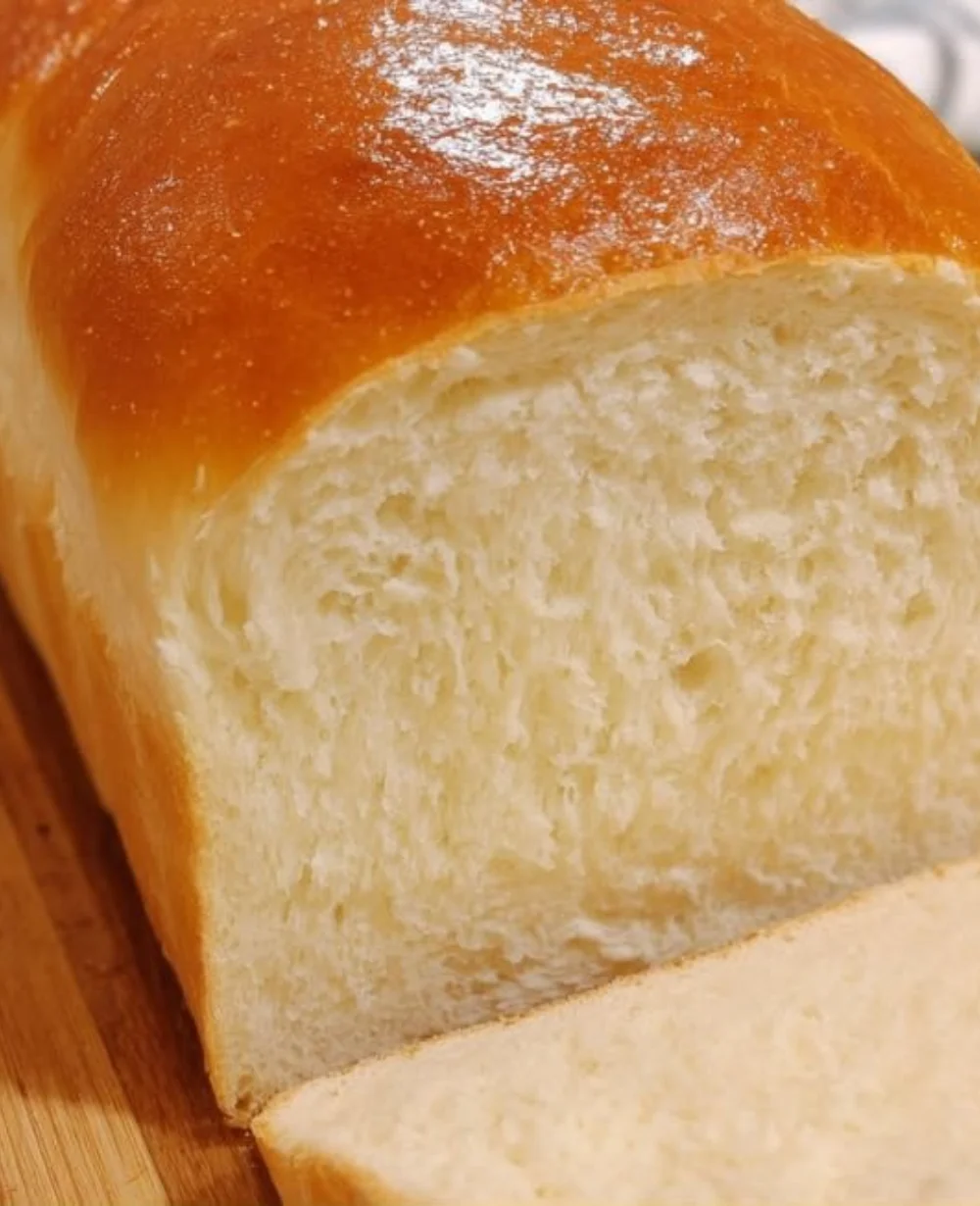 Loaf of freshly baked homemade white bread on a wooden cutting board.