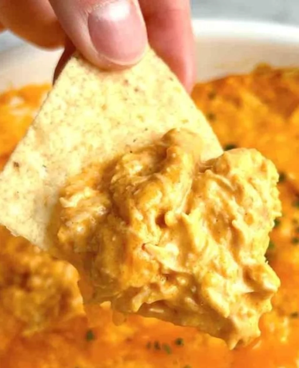 A bowl of spicy Buffalo Chicken Dip with tortilla chips on the side.