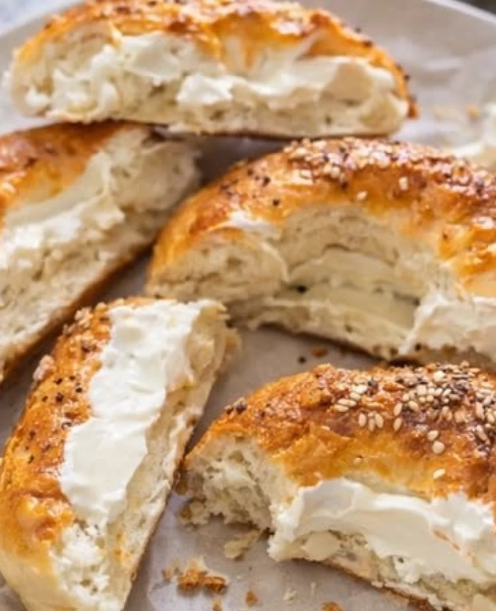 Freshly baked Cottage Cheese Bagels on a wooden table with toppings.