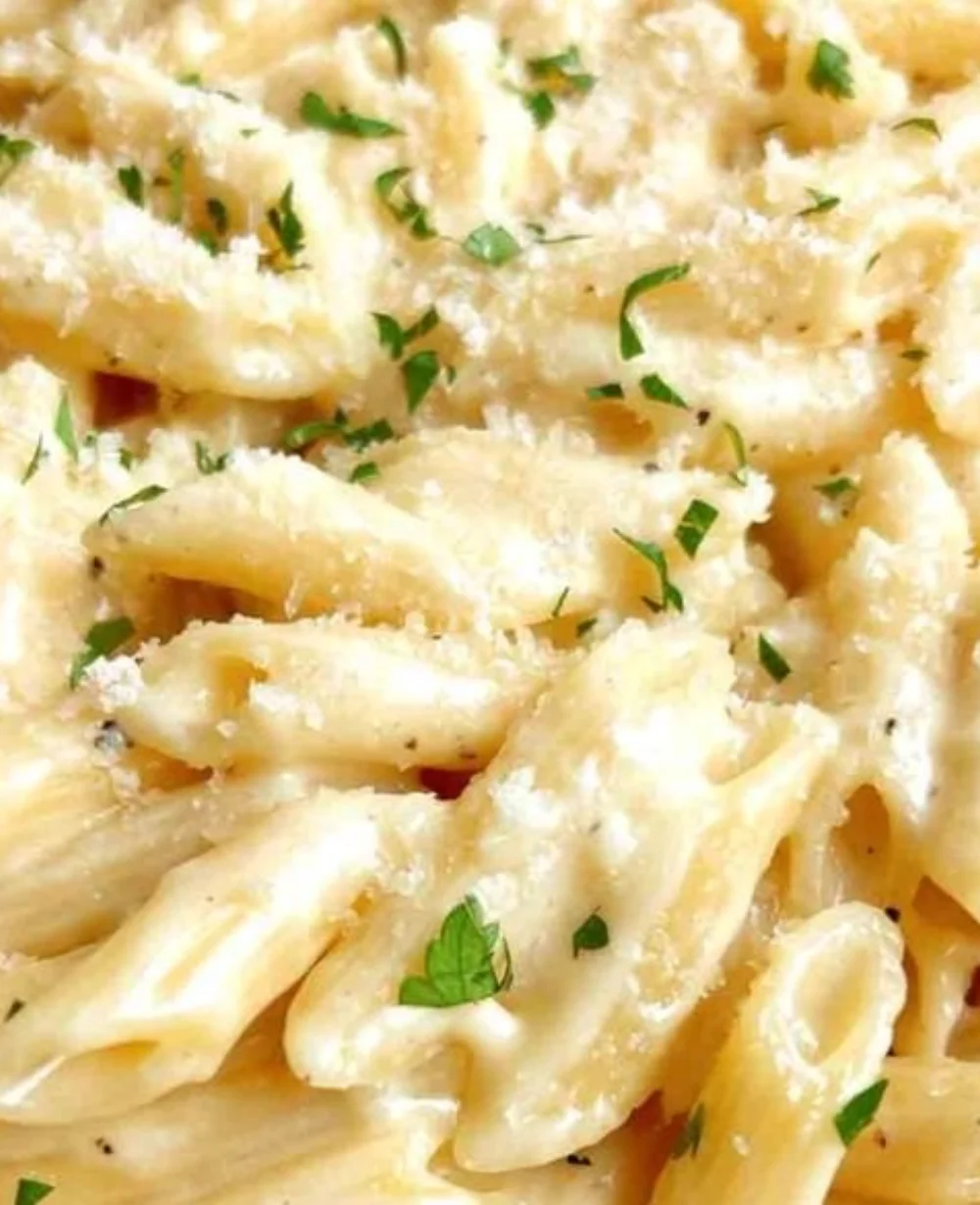 A delicious plate of creamy garlic pasta topped with herbs and parmesan cheese.