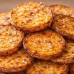 Crispy air fryer potato rounds served on a plate with dipping sauce.