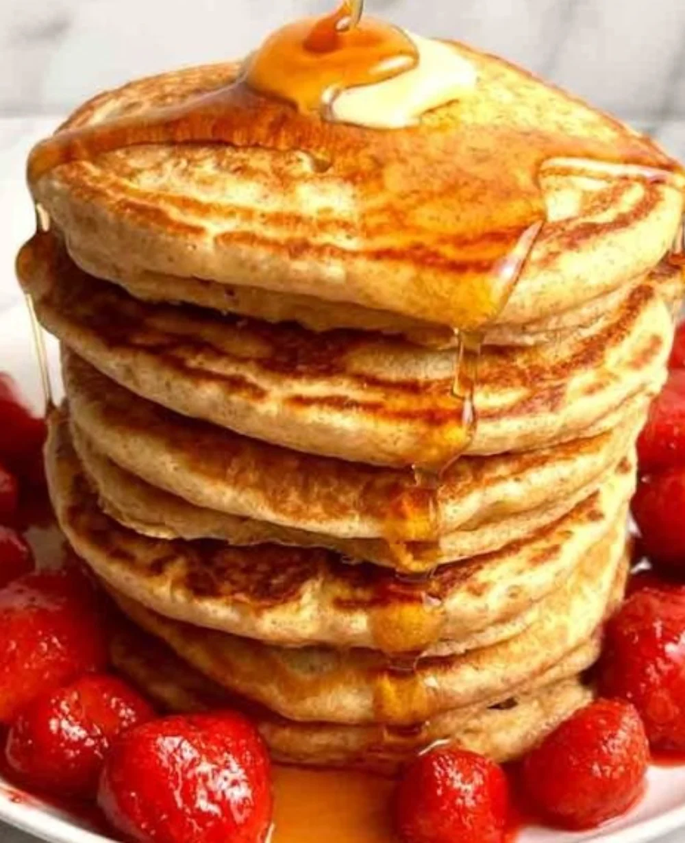 Plate of fluffy whole wheat pancakes topped with fresh berries and maple syrup