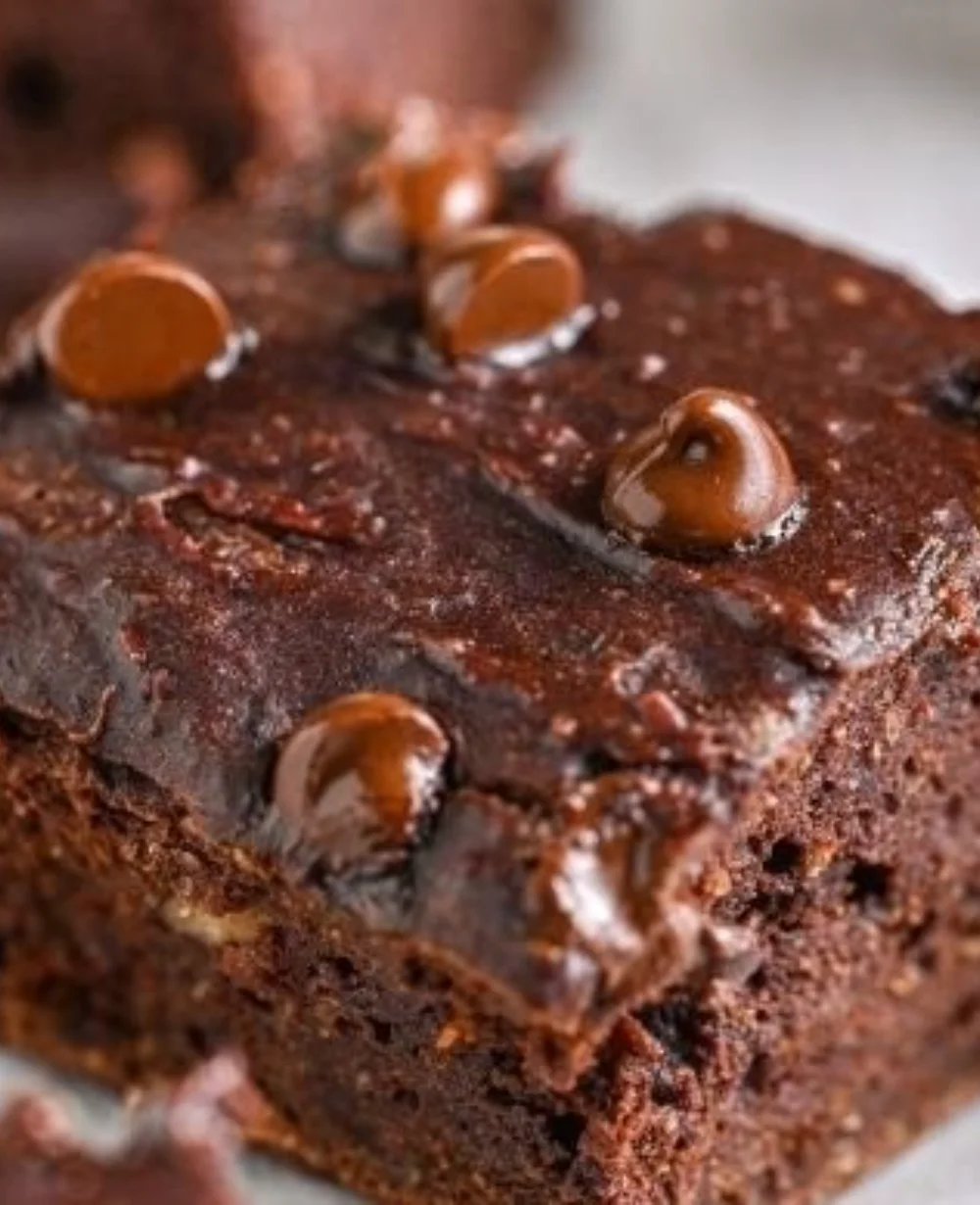 Flourless pumpkin brownies served on a plate topped with chocolate drizzle.