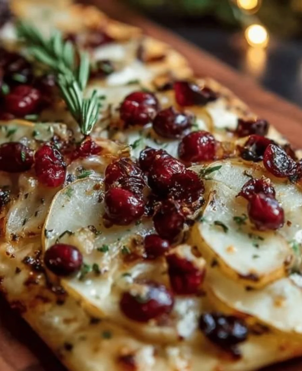 Pear, brie, and cranberry flatbread topped with fresh herbs and drizzled with balsamic glaze