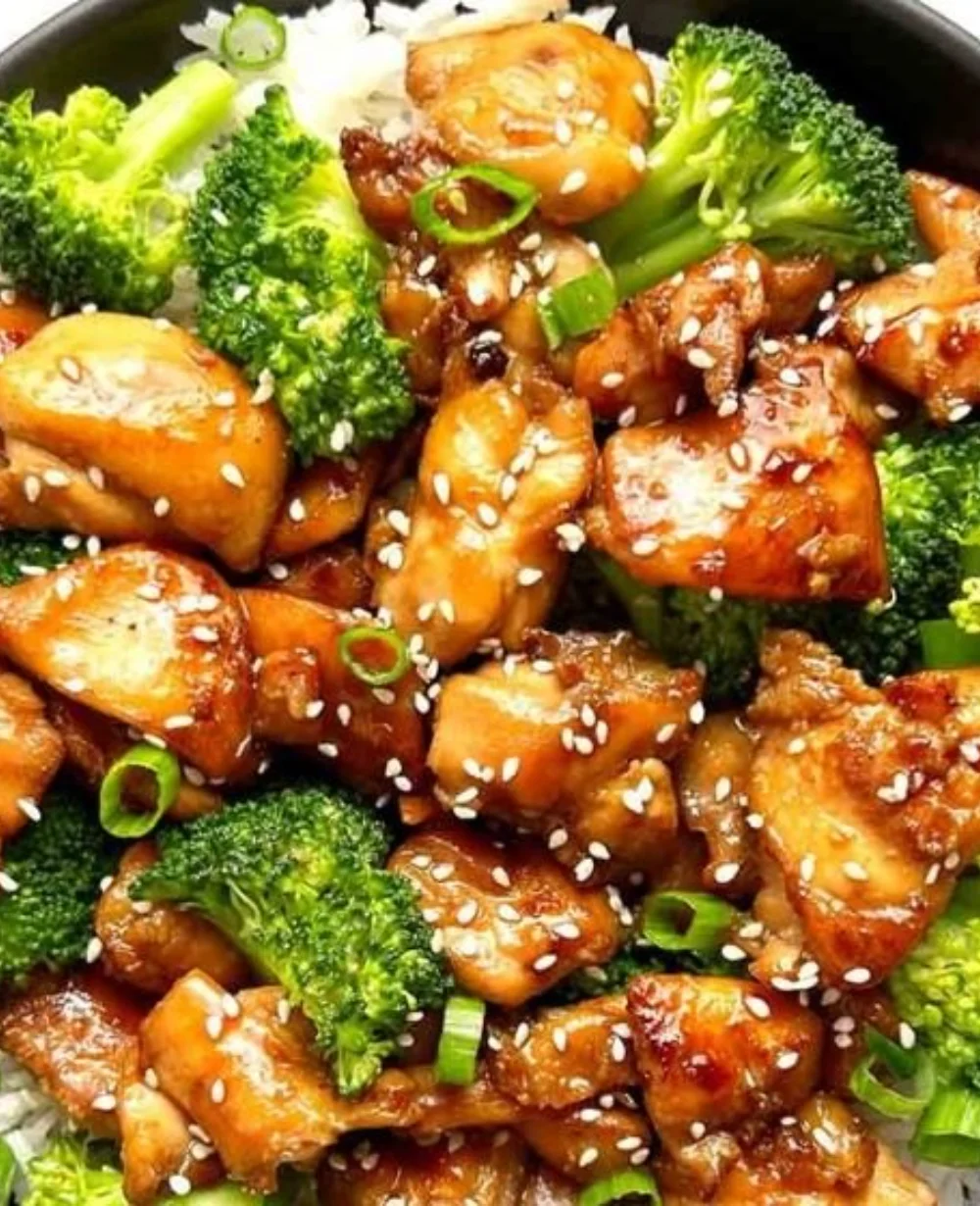 Delicious teriyaki chicken rice bowl garnished with vegetables and sesame seeds.