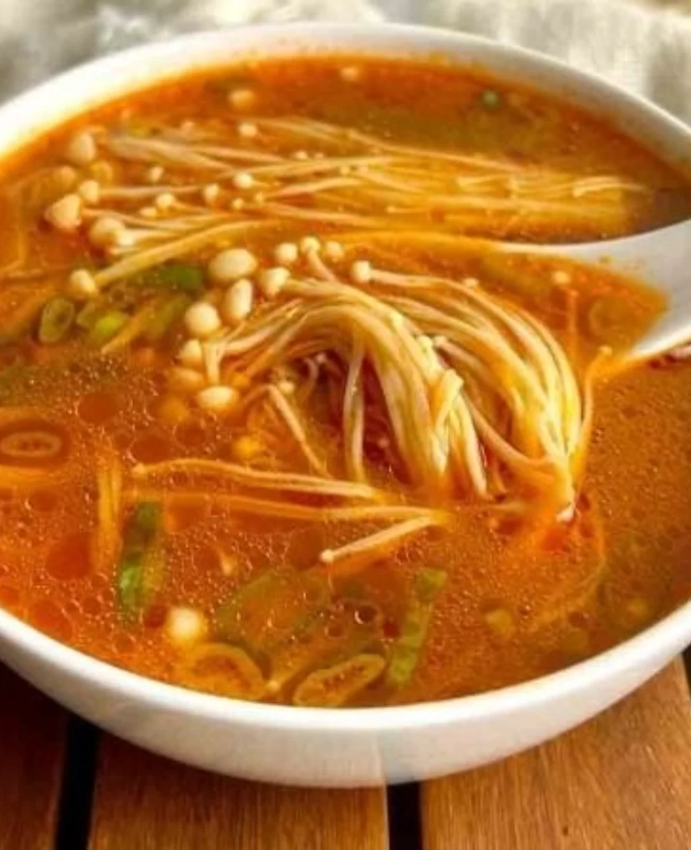 Bowl of Tomato Enoki Mushroom Soup garnished with fresh herbs