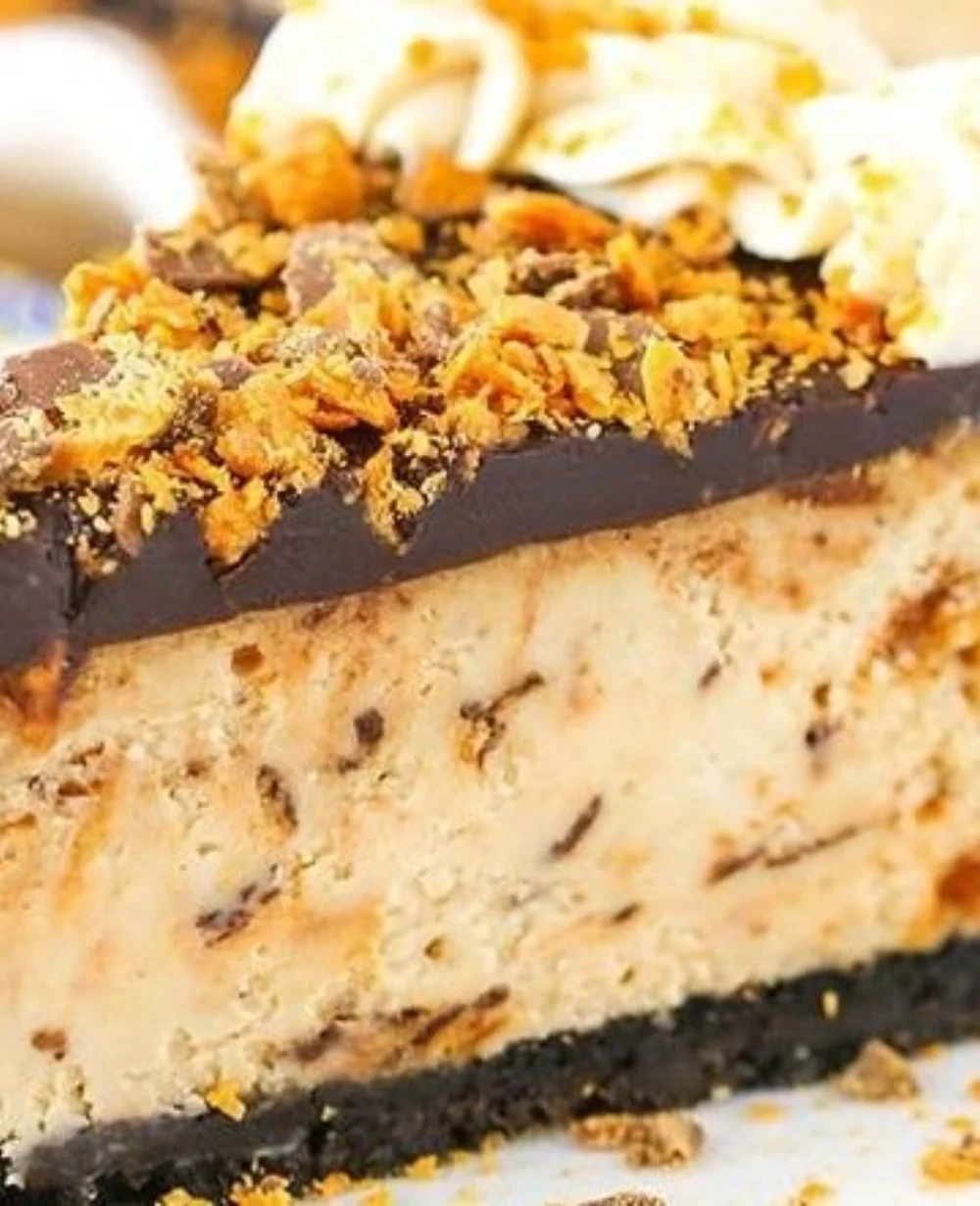 Deliciously creamy Butterfinger cheesecake topped with crushed candy bars.