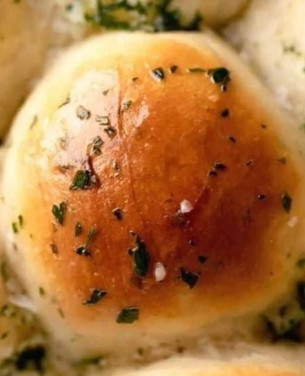 Freshly baked garlic butter dinner rolls on a wooden table.