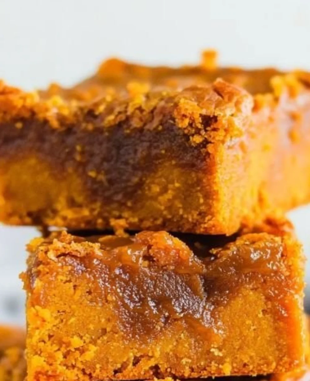 Sweet potato blondies topped with salted caramel sauce on a rustic wooden table.