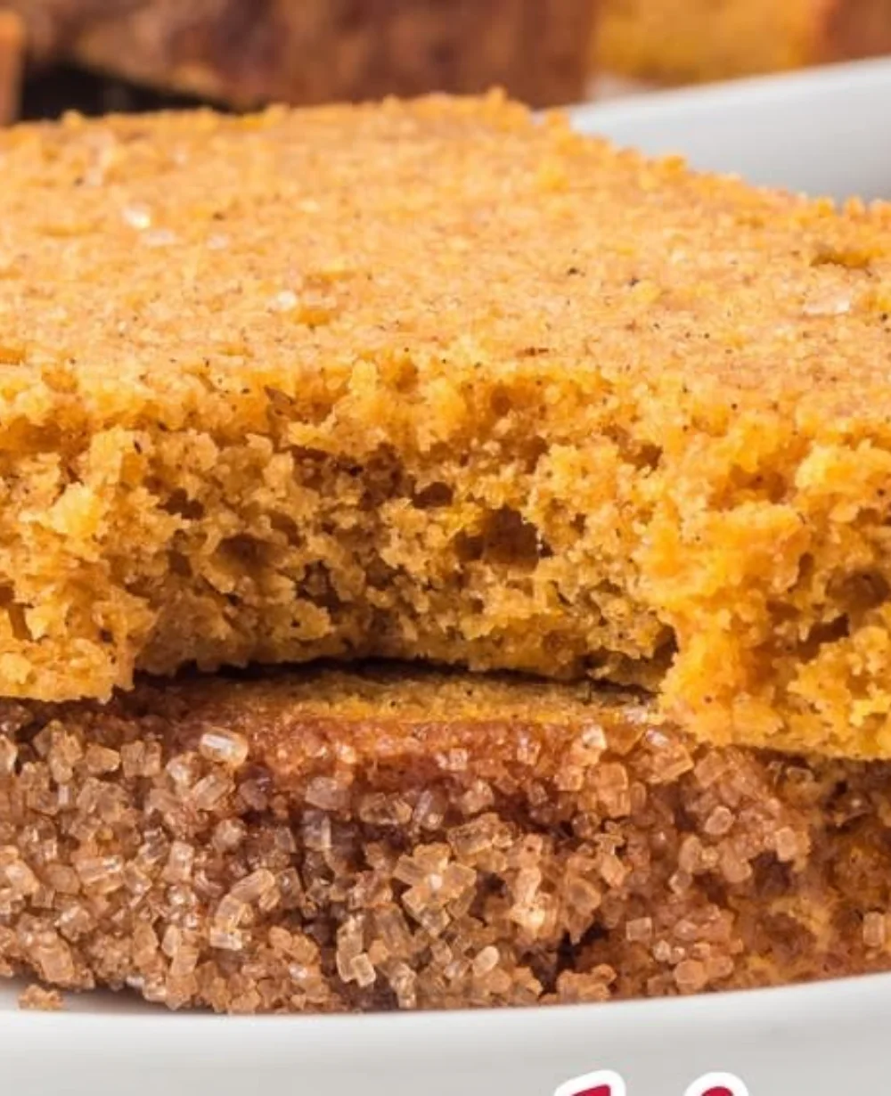 A slice of easy pumpkin bread topped with butter on a wooden table.