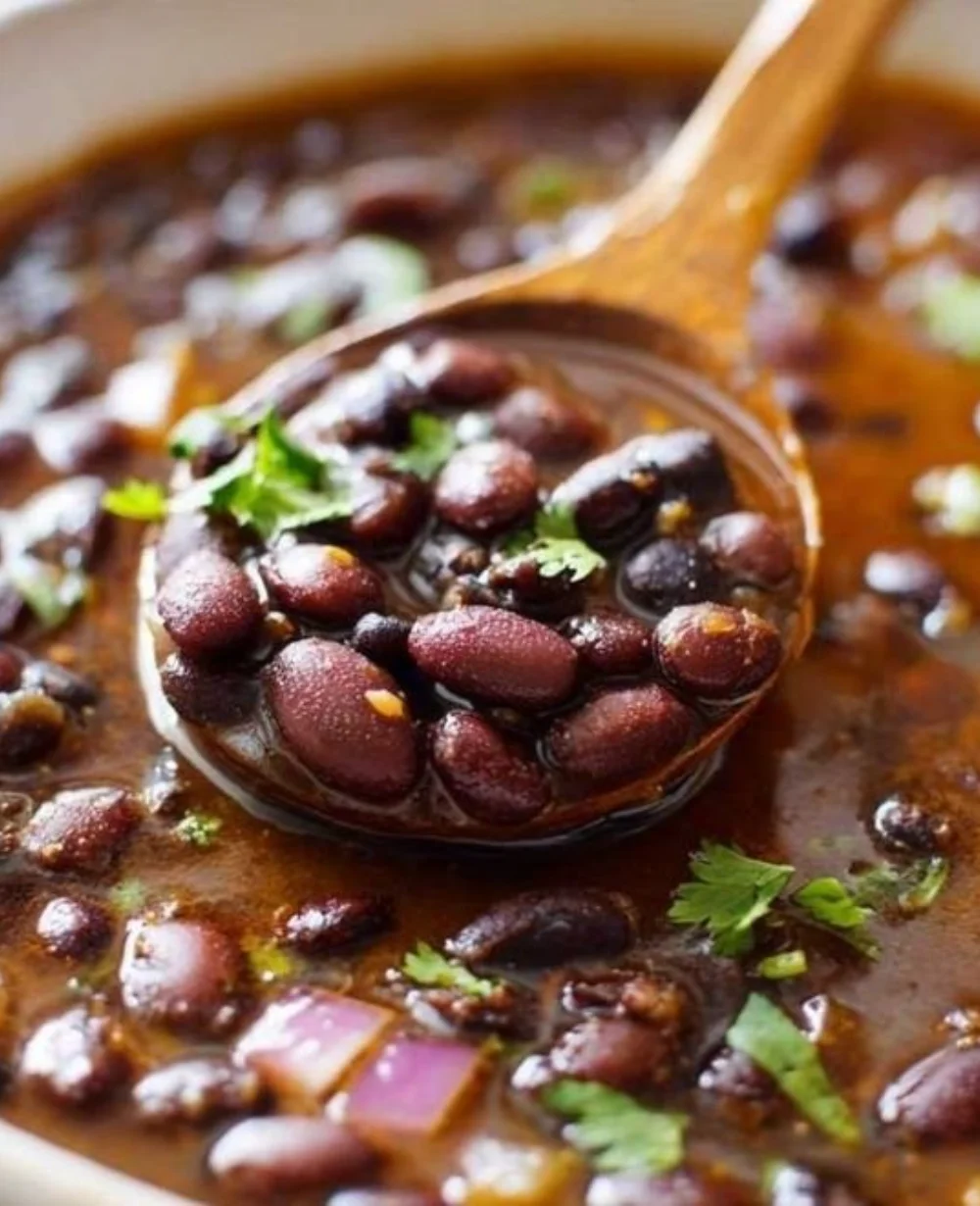 Bowl of homemade Mexican-style black beans garnished with herbs.