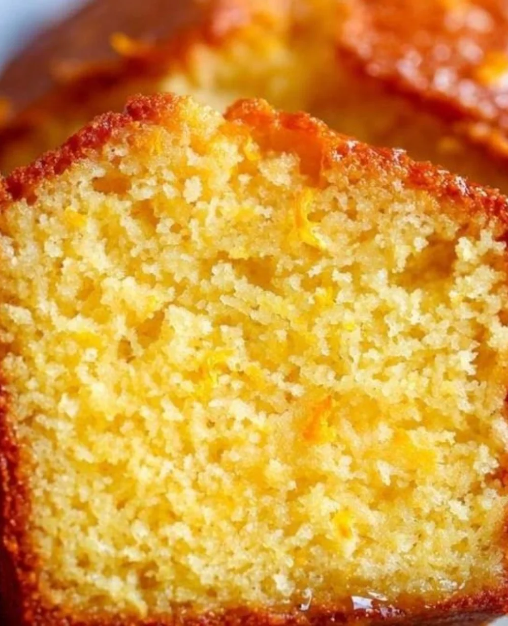 Loaf of orange bread with vibrant citrus glaze and slices cut on a wooden board