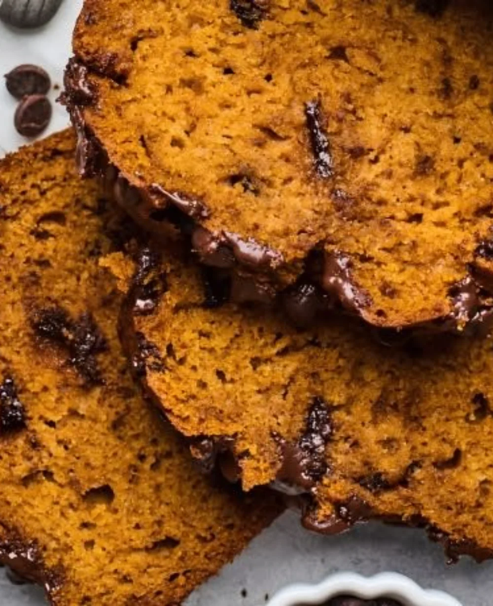 Loaf of homemade Pumpkin Chocolate Chip Bread with chocolate chips on a plate