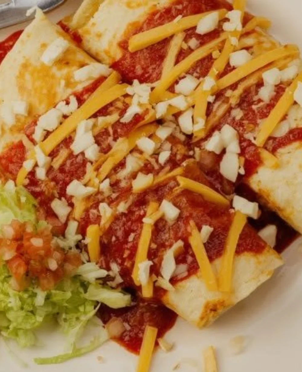 Smothered bean burrito topped with savory sauces and garnished with fresh ingredients.